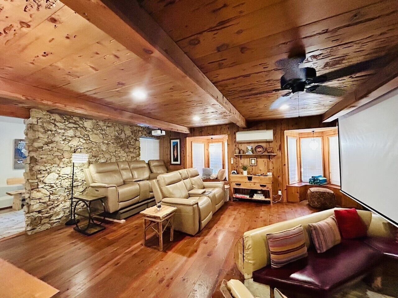 Un salon chaleureux avec un mur en pierre, un plafond en bois et une cheminée.