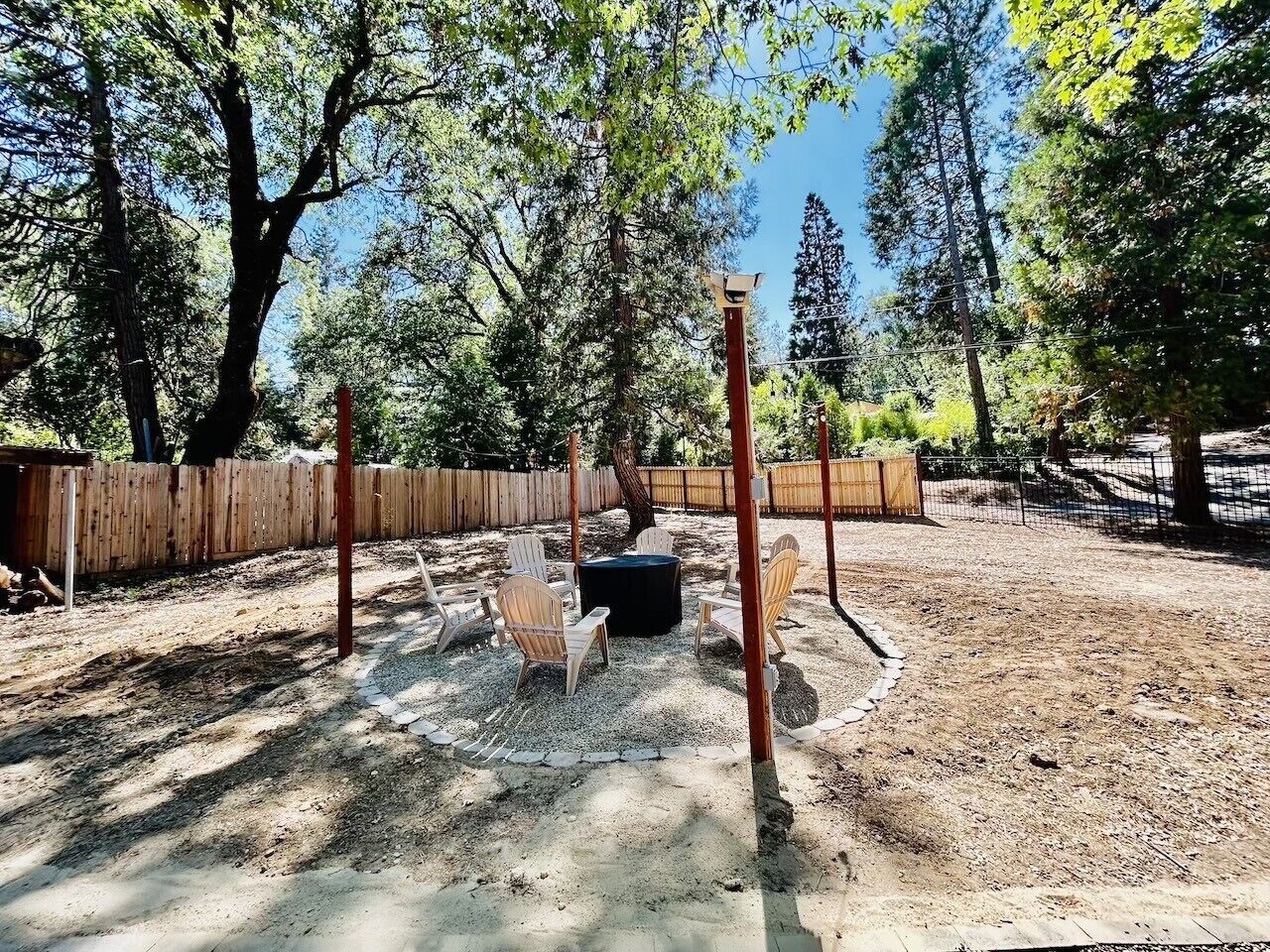 An outdoor seating area with chairs and a table, surrounded by a wooden fence and trees.