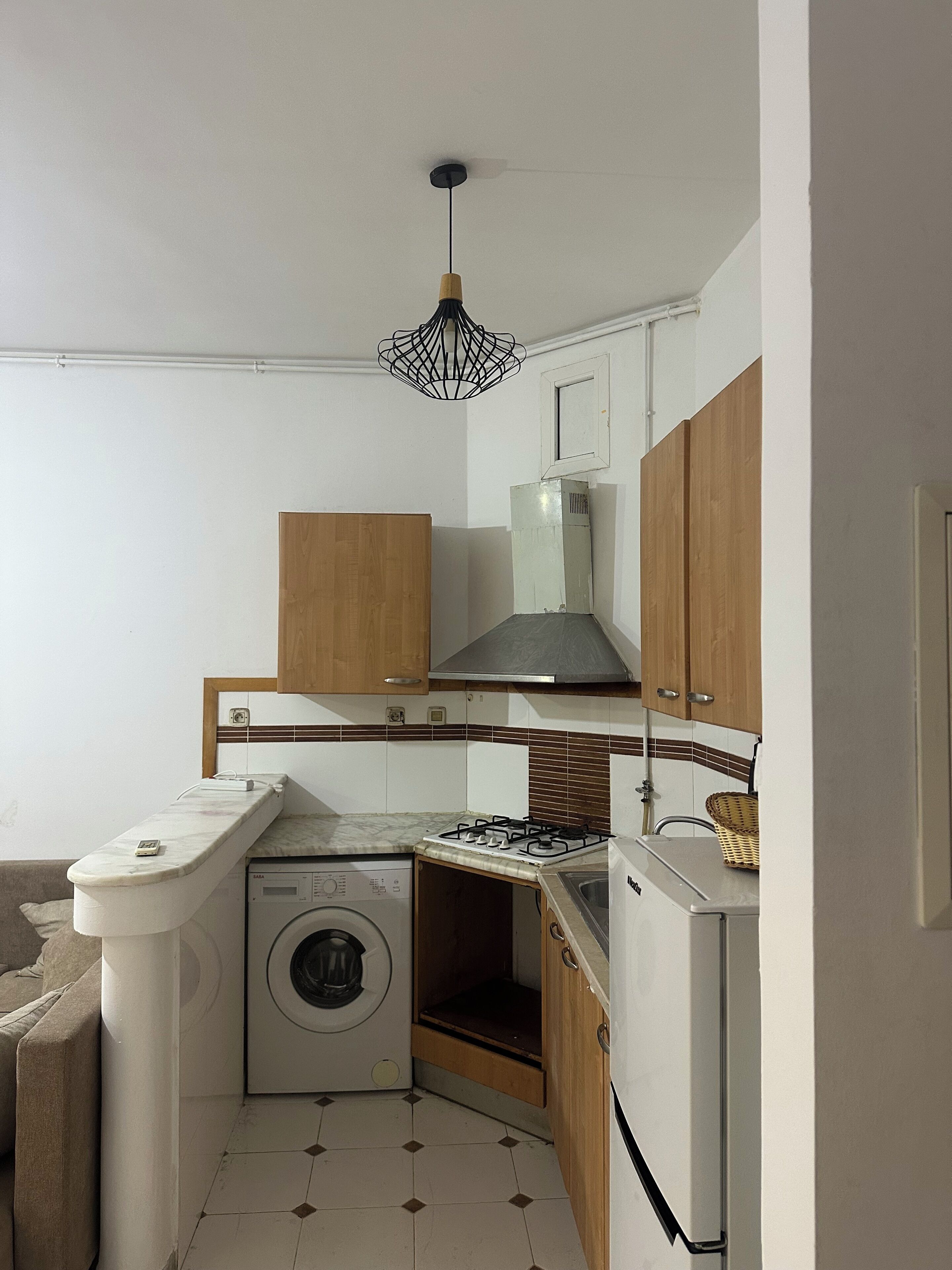 Una cocina compacta con lavadora, estufa a gas y muebles de madera.