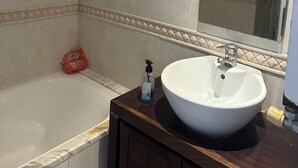 Ein Badezimmer mit einer Badewanne, einem Waschbecken mit Spiegel und einem Seifenspender.