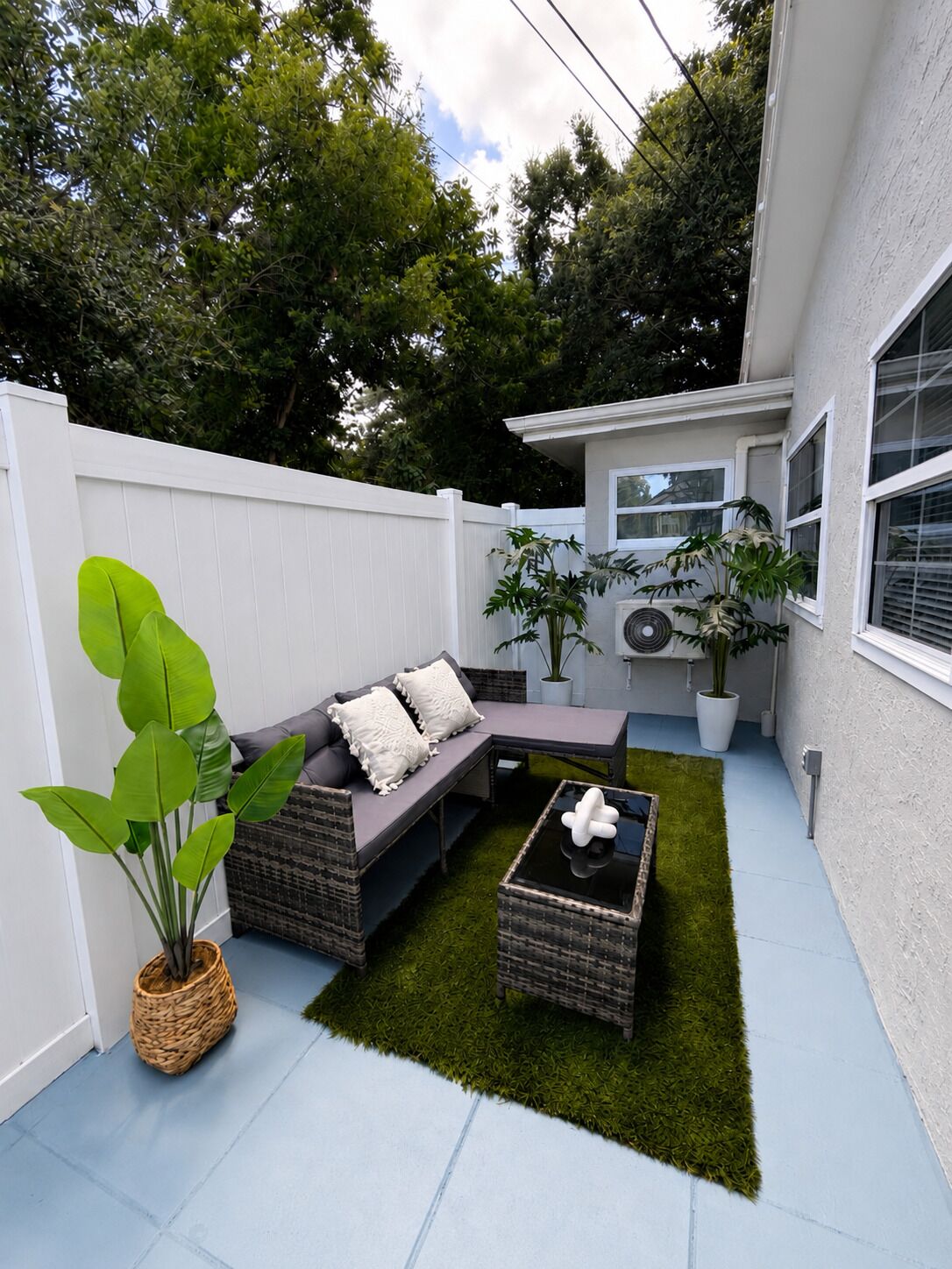 A patio with a sectional sofa, a coffee table, and potted plants.