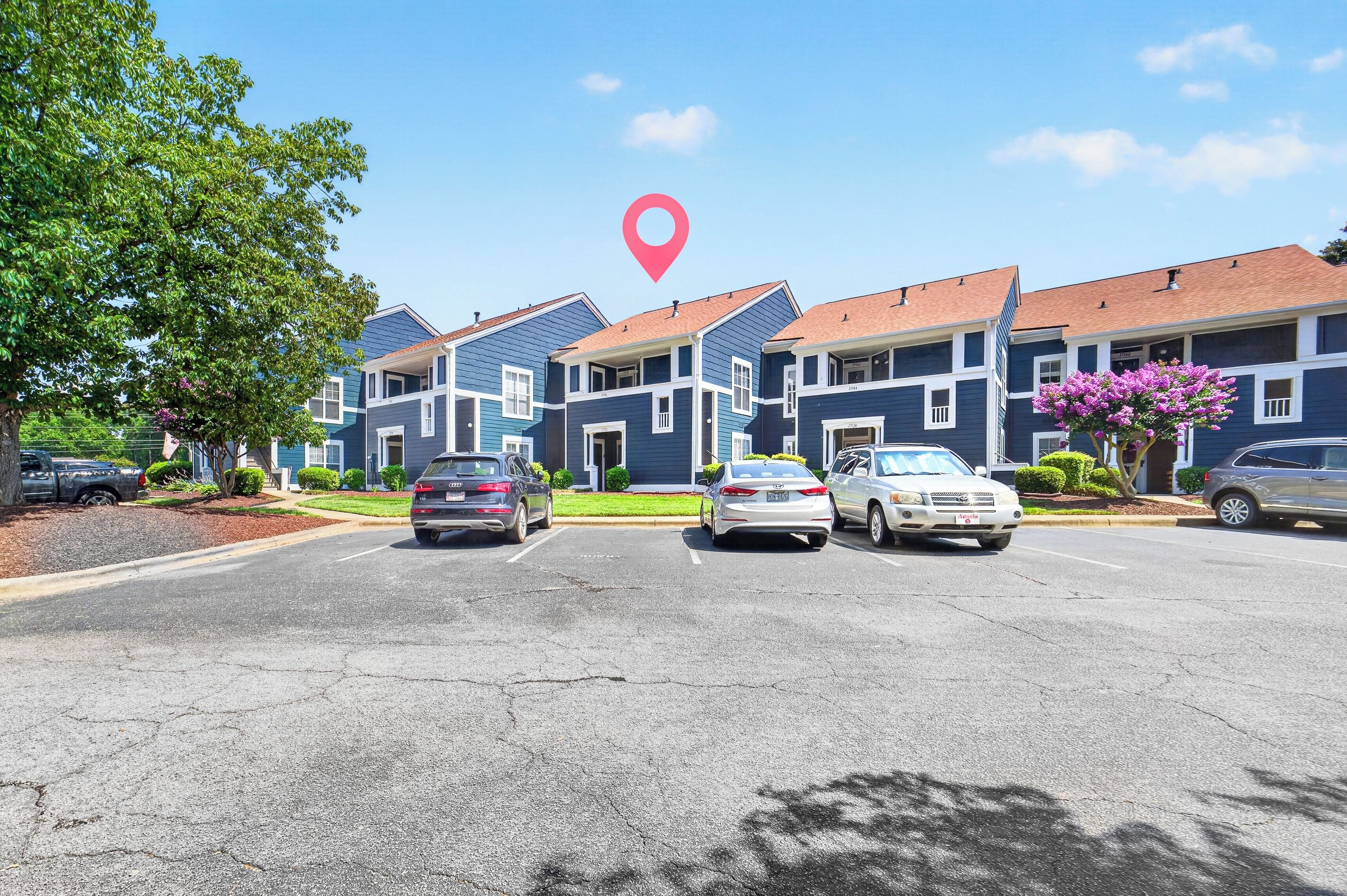 A row of townhouses with a parking lot in front.