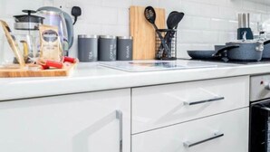 A modern kitchen with white cabinets, a coffee maker, a kettle, and various utensils. - NEW 3BR Stylish Home Near NEC | HS2 | JLR | Resorts World & B'ham Airport (Birmingham)