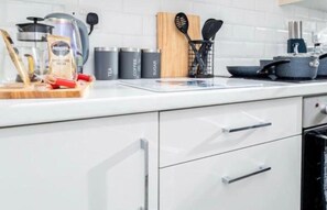 Eine moderne Küche mit weißen Schränken, einer Kaffeemaschine, einem Wasserkocher und verschiedenen Küchenhelfern.