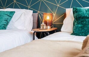 Ein Hotelzimmer mit zwei Betten, einem Kopfteil mit geometrischem Muster und einem Nachttisch mit Lampe.