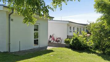 A residential building with a bicycle parked outside, a well-maintained lawn, and a clear sky.