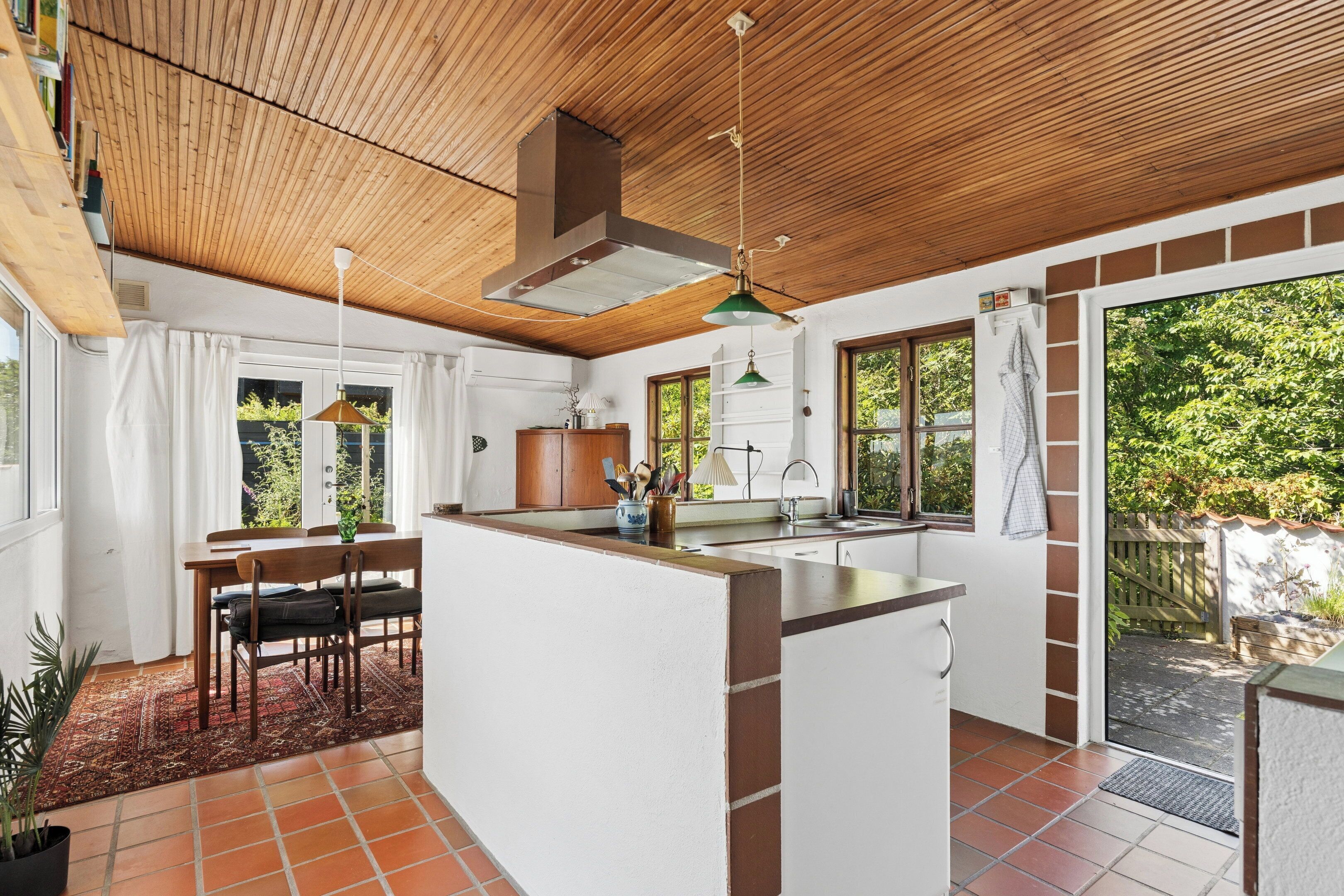 A kitchen with a central island, wooden ceiling, and large windows.