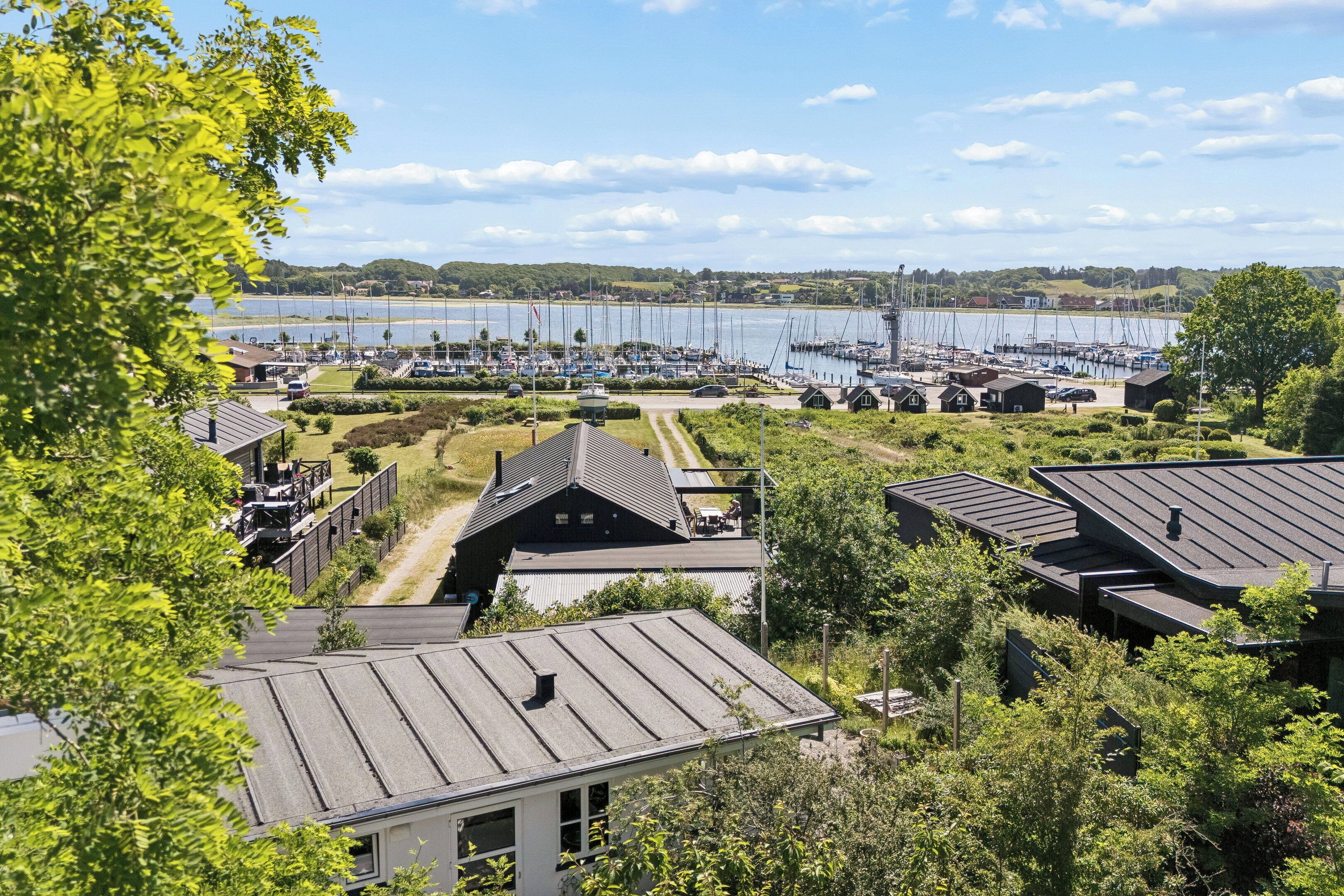 A marina with boats, houses with metal roofs, and a clear sky.