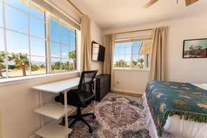 Habitación de hotel con escritorio, cama y dos ventanas con cortinas.