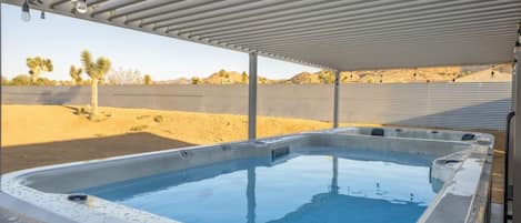 Ein Whirlpool unter einer überdachten Terrasse mit einer Wüstenlandschaft im Hintergrund.