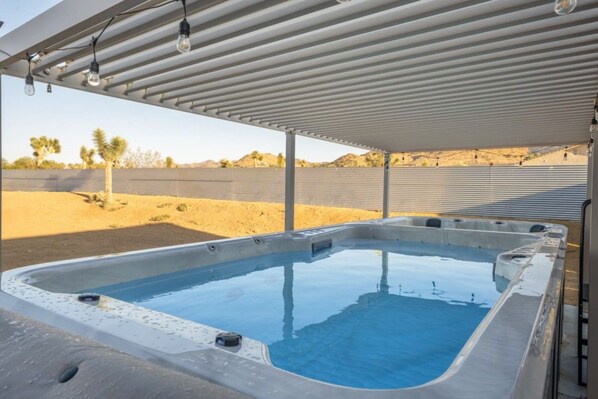Un bain à remous sous un patio couvert, avec un paysage désertique en arrière-plan.