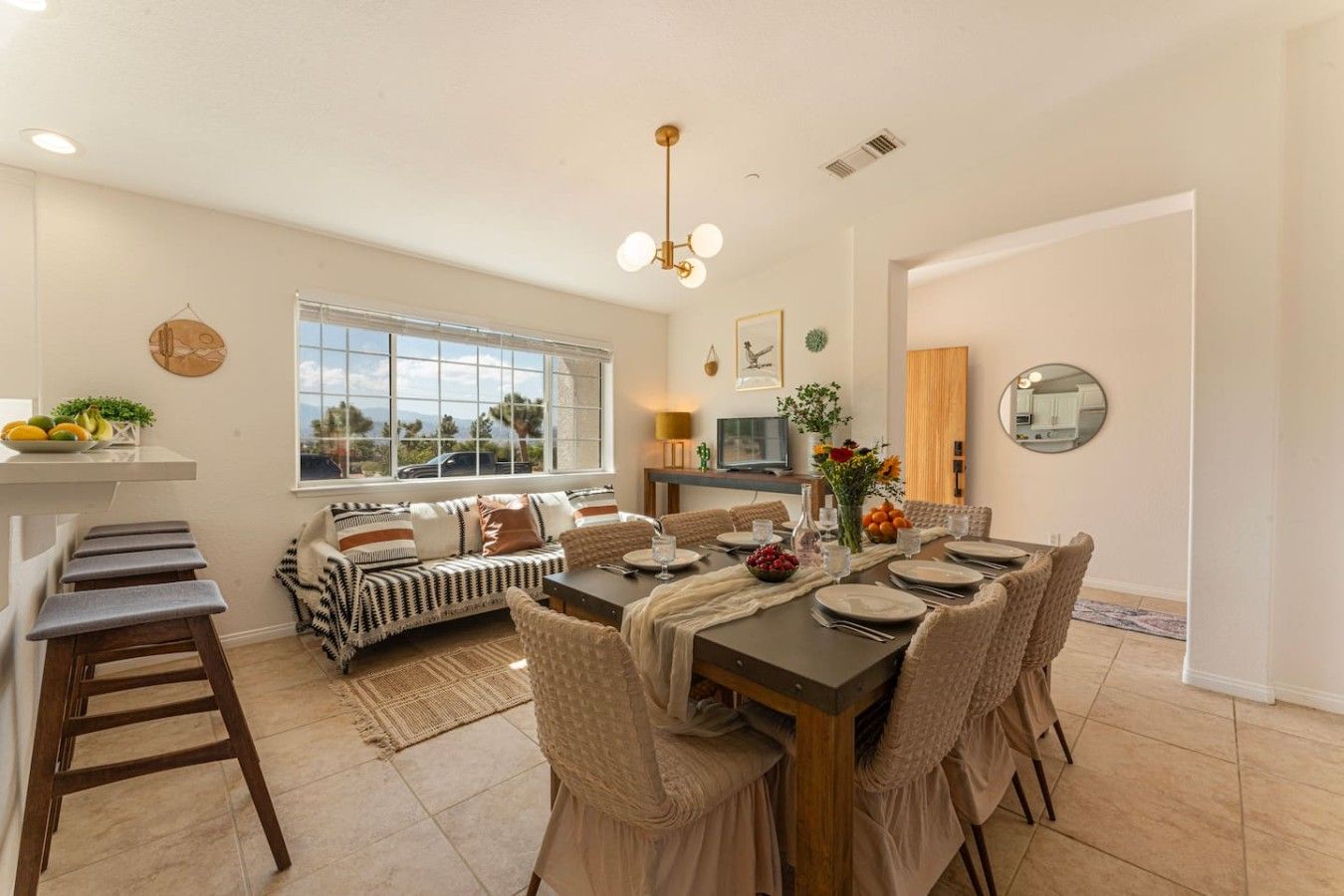 Un coin repas avec une table dressée pour quatre personnes, un canapé et, au fond, un espace cuisine.