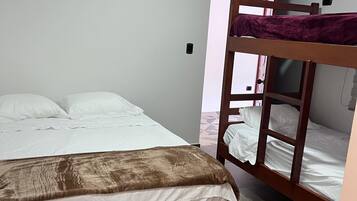 A room with a single bed, a bunk bed, a ceiling fan, and a window with curtains.