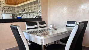 Un tavolo da pranzo con quattro sedie, una cucina sullo sfondo e un pannello decorativo.