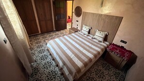Una camera da letto con un letto, un armadio, un comodino e un pavimento decorato.