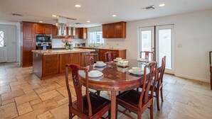 Una cocina amplia con una isla central, armarios de madera y un comedor con una mesa redonda y sillas.