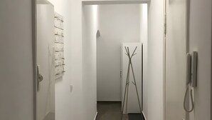 A narrow hallway with white walls, a door with a branch-like decoration, and a wall-mounted phone. - Apartment for 4 Guests, 55 m², with Wi-Fi (Berlin)