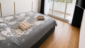 A bedroom with a bed, a TV, and a balcony with a view. - Sunny Algarve: Duplex with ocean views in Armação de Pêra. (Armação de Pêra)