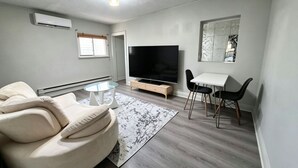 En moderne stue med sofa, TV og spiseplads.