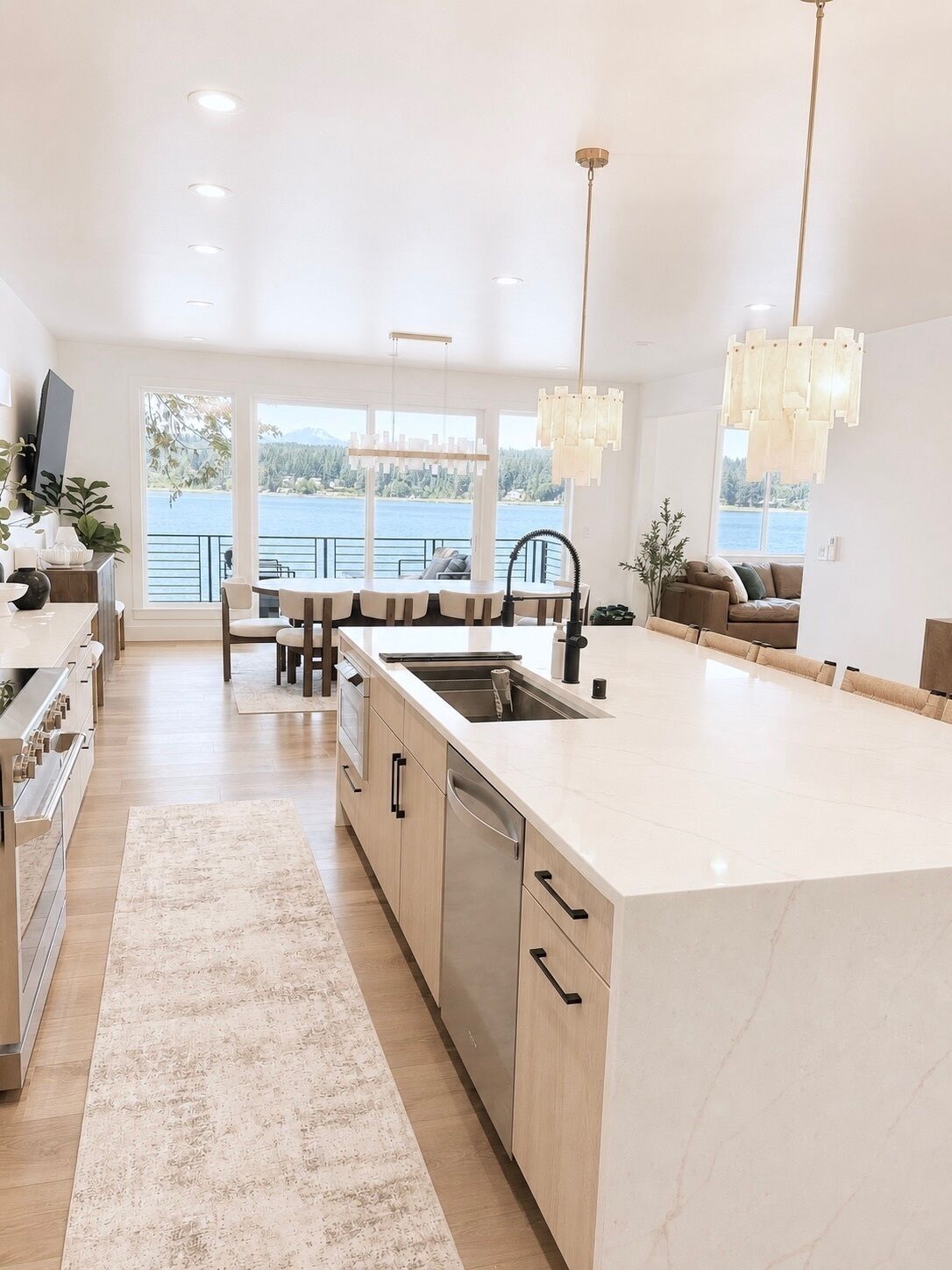 Une cuisine moderne dotée d’un grand îlot central, d’un coin repas offrant une vue agréable et d’un espace de vie avec un canapé.