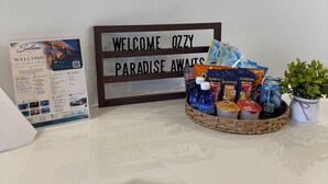 En receptionsdisk med en välkomstskylt, en broschyr, en korg med snacks och en liten växt.