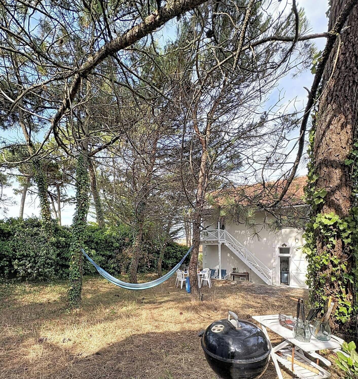 A hammock in a backyard with a barbecue grill and outdoor furniture.