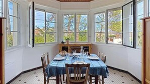 Ein Essbereich mit einem runden Tisch, Stühlen und Blick durch große Fenster.