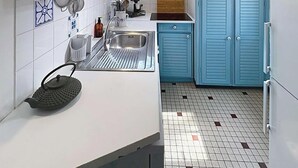 Eine Küche mit Spüle, Wasserkocher und blauen Schränken.