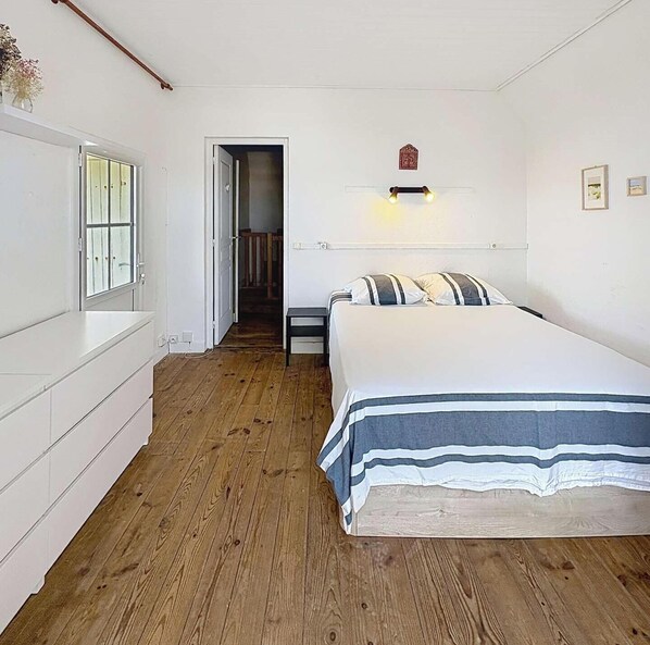 Ein Schlafzimmer mit einem Bett, einem Nachttisch, einer Kommode und einer Tür zu einem anderen Raum.