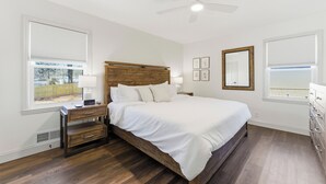 Quarto com cama de madeira, mesa de cabeceira, escrivaninha e cómoda.