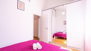 Ein Schlafzimmer mit einem Bett, einem Spiegel und einer Tür zu einem anderen Raum.