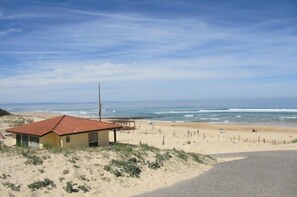 Ein Strand mit einem Gebäude, einer Straße und dem Meer.