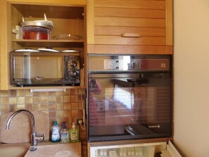 Eine Küche mit Mikrowelle, Backofen und verschiedenen Küchengeräten.