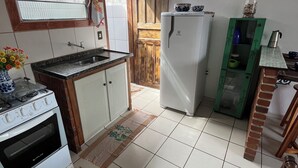 Eine Küche mit Herd, Spüle, Kühlschrank und einem Fenster mit Jalousien.