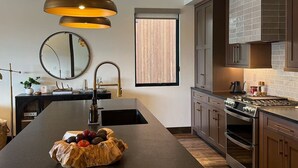 A modern kitchen with a central island, stainless steel appliances, and a large window. - Lakeside Luxury: Hottub+Sauna+Fire Pit+Kid Friendly+Lake View+Mountain View (Whitefish)