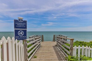 A wooden boardwalk leading to the beach with signs indicating beach access requirements and a no dogs policy. - Hydrangea Lane Beach Cottage (Mashpee)
