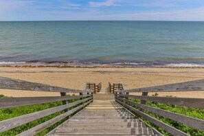 A wooden staircase leading to a beach with a view of the ocean. - Hydrangea Lane Beach Cottage (Mashpee)