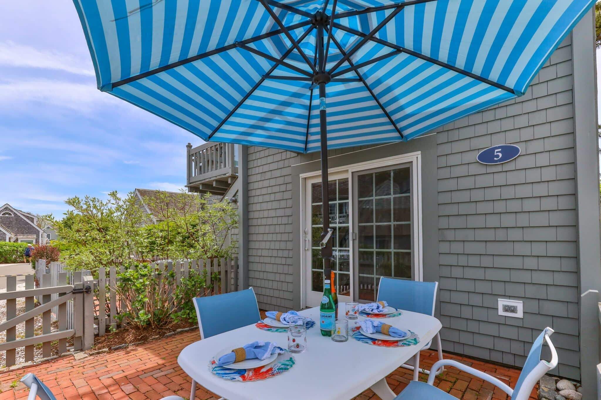 A patio with a table set for two, an umbrella, and a house number 5.