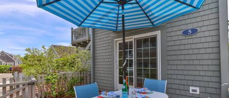 A patio with a table set for two, an umbrella, and a house number 5.