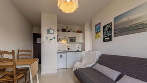 A compact living space with a kitchenette, a dining area, and a sofa. - T3 apartment near the beach in Fréhel | 4 guests | Ref 117 (FREHEL)