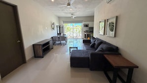 A modern living room with a sofa, a coffee table, a TV, and a dining area with chairs and a table. - Comfortable apartment with a pool and hot tub. (Las Jarretaderas)