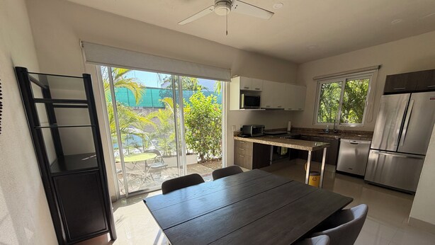 A modern kitchen with a dining area, large windows, and a view of greenery outside. - Comfortable apartment with a pool and hot tub. (Las Jarretaderas)