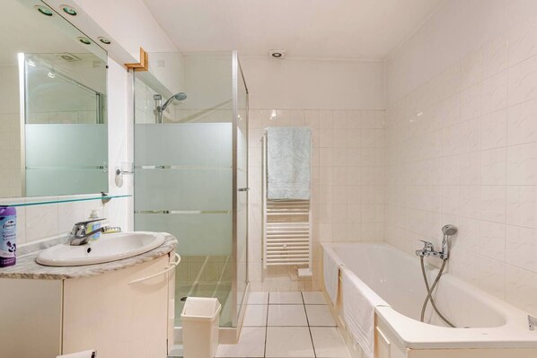 Une salle de bain avec une douche à parois de verre, une baignoire, un lavabo et un miroir.