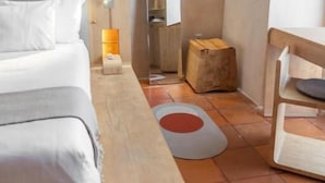 Ein Schlafzimmer mit einem Bett, einem Nachttisch aus Holz, einem Spiegel, einem kleinen Tisch und einem roten und weißen Teppich.