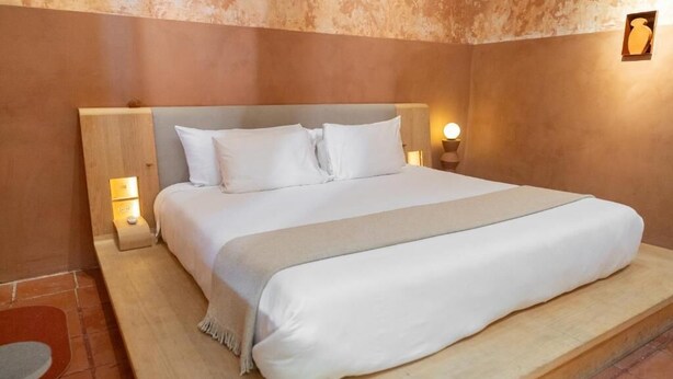 Ein Bett mit weißer Bettwäsche, zwei Nachttischlampen und einem hölzernen Kopfteil.