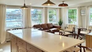 Une cuisine moderne dotée d’un grand îlot central, de meubles en bois et de luminaires suspendus.