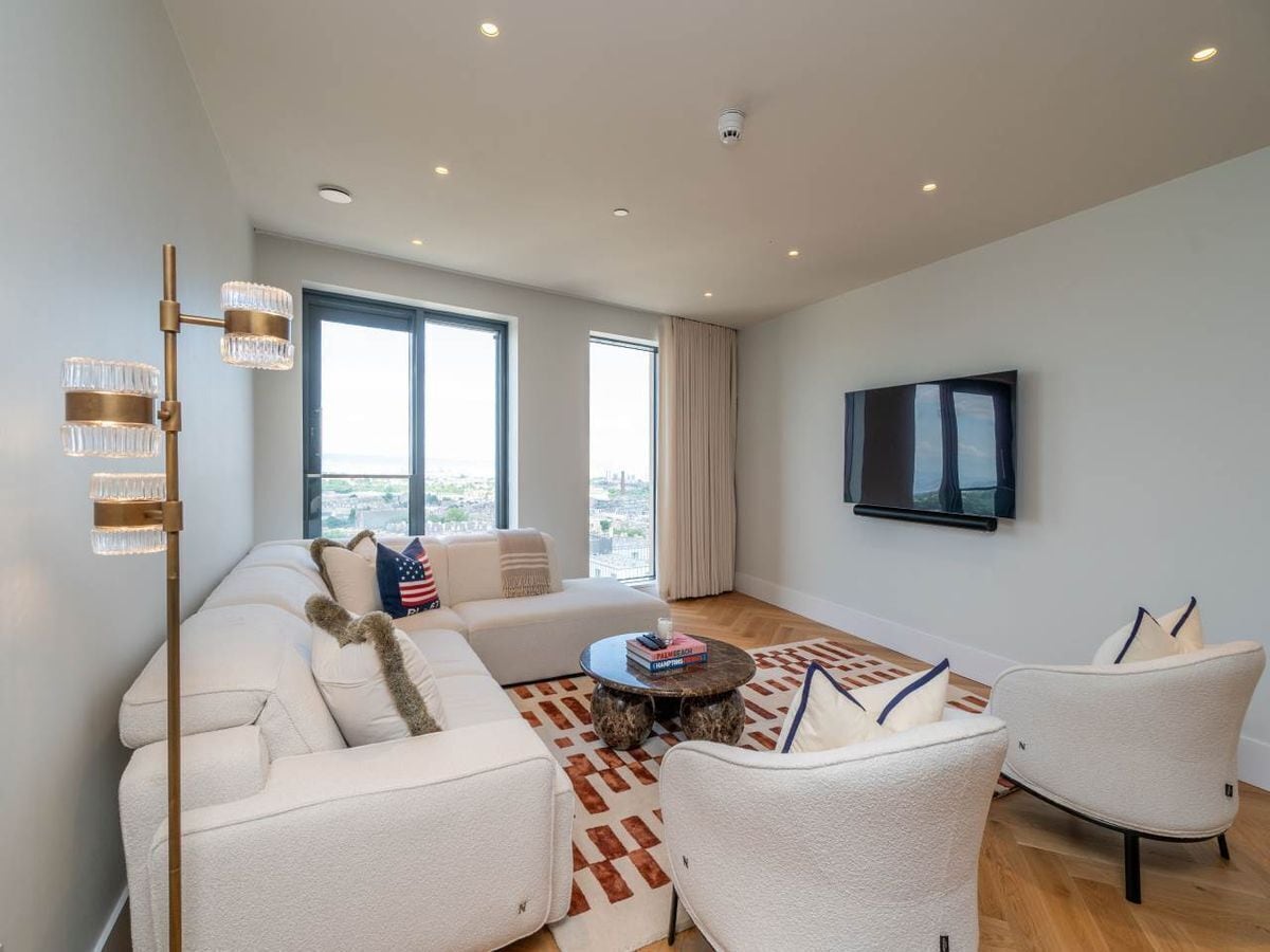 A modern living room with a sofa set, a coffee table, and a TV mounted on the wall.