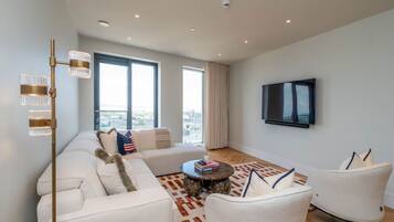 A modern living room with a sofa set, a coffee table, and a TV mounted on the wall.
