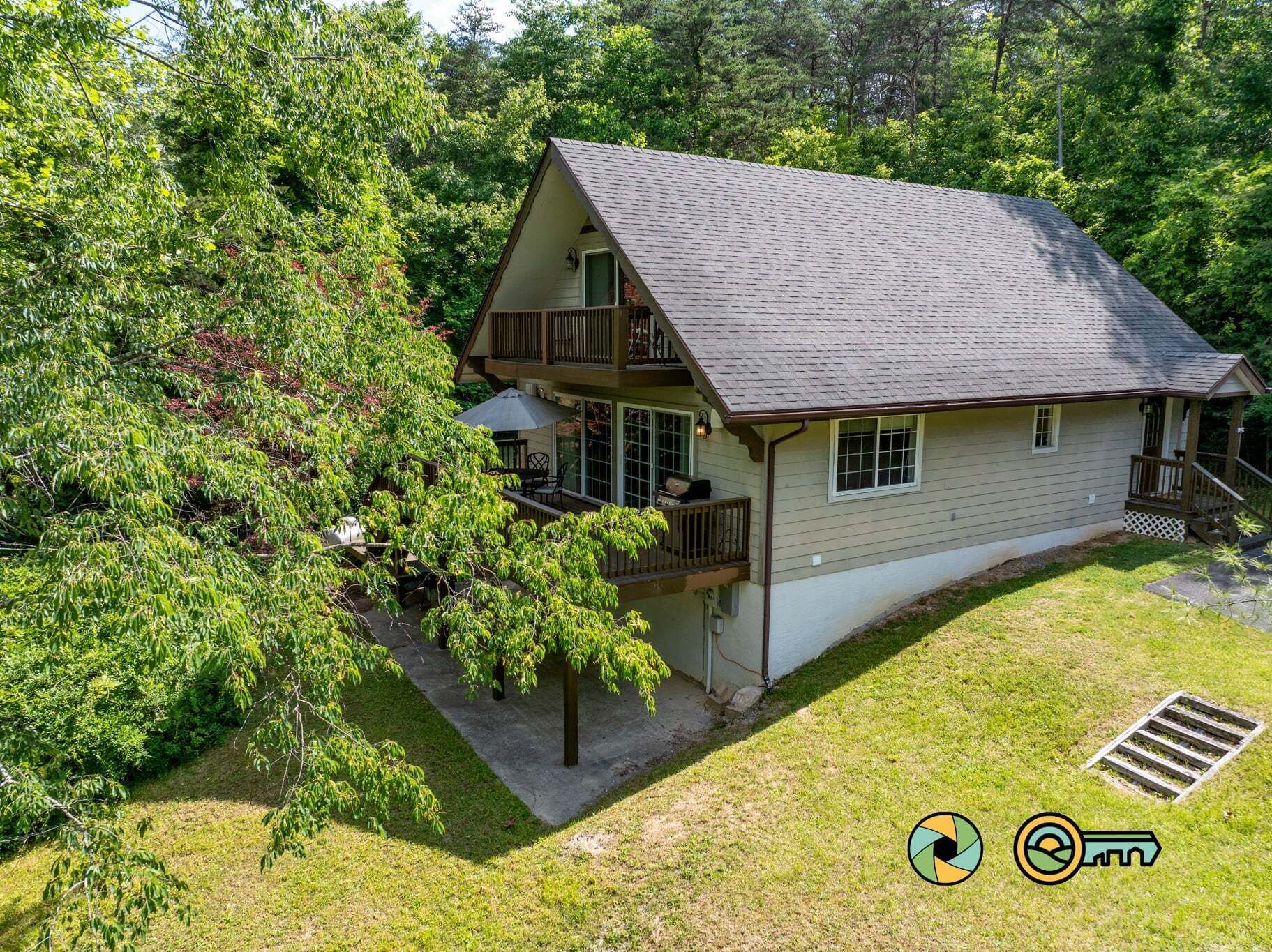 A two-story house with a balcony, surrounded by lush greenery.