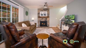 A living room with a fireplace, leather chairs, a sofa, and a television.
